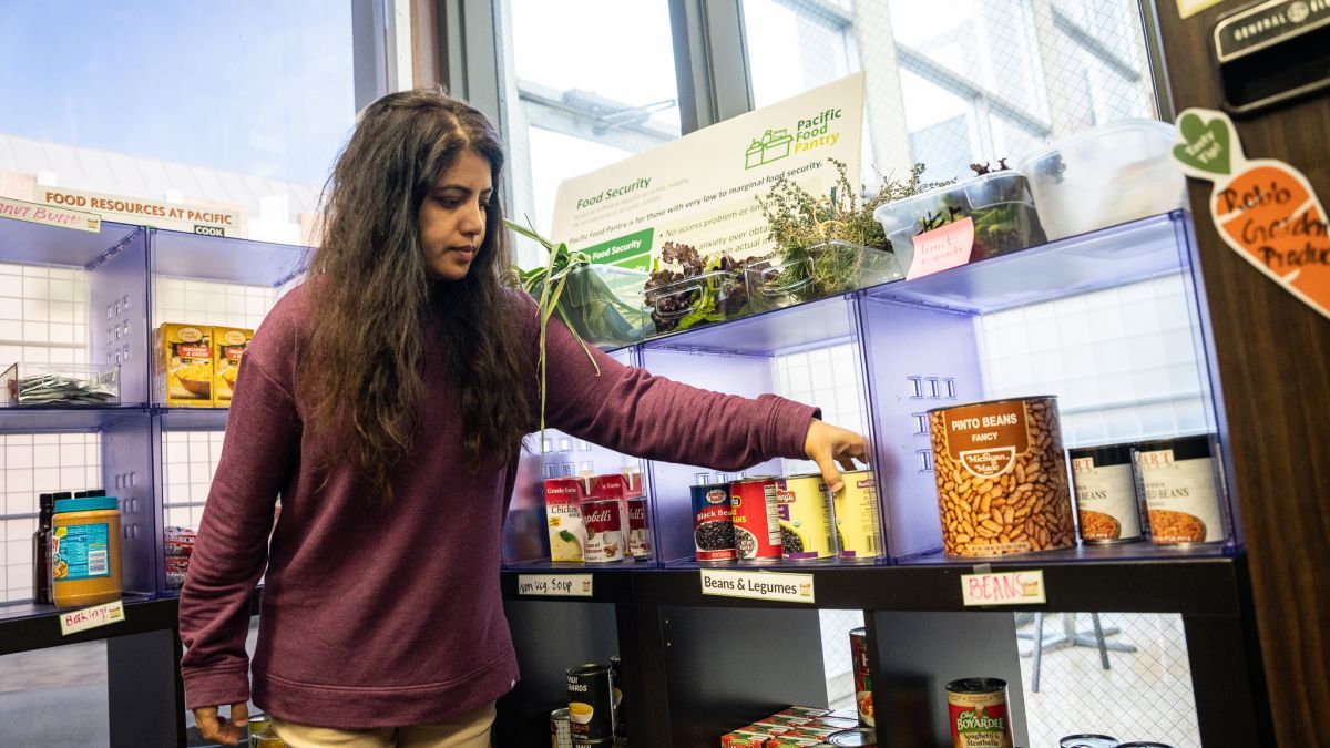 student worker restocks food pantry