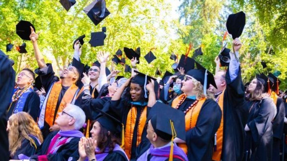 Graduate throw their caps in the air.