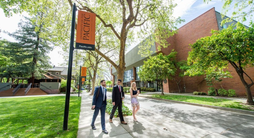 Three students walk across campus